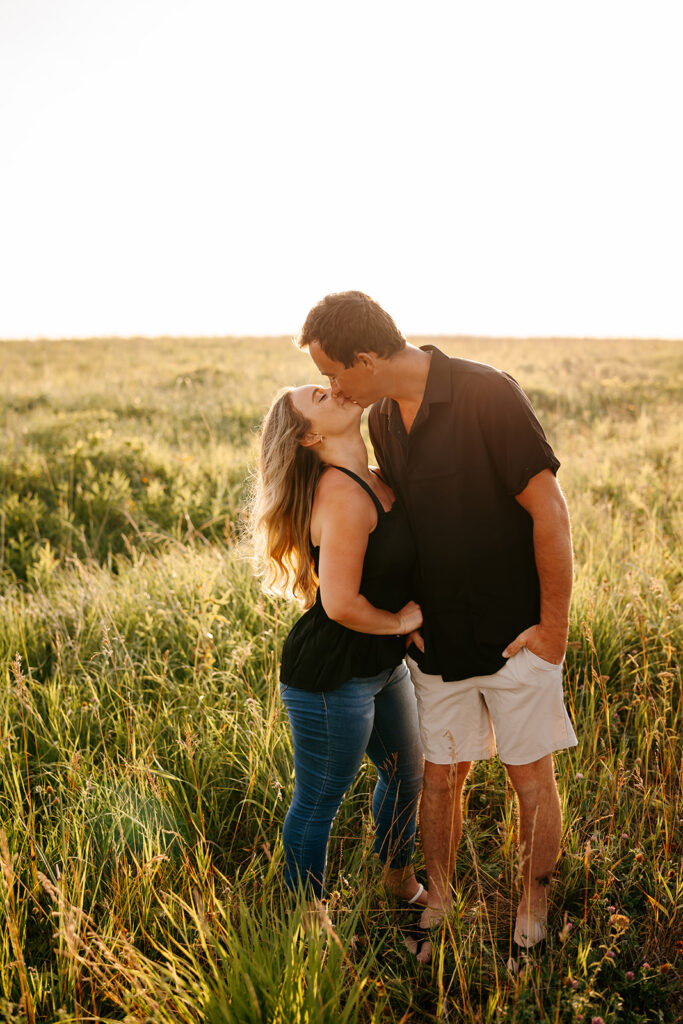 Couple kissing in the grasslands at sunrise