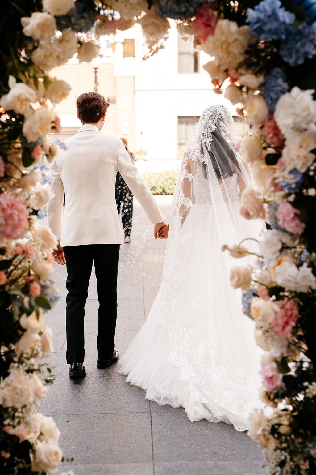 Couple walking through floral ceremony arch at Hotel Carmichael
